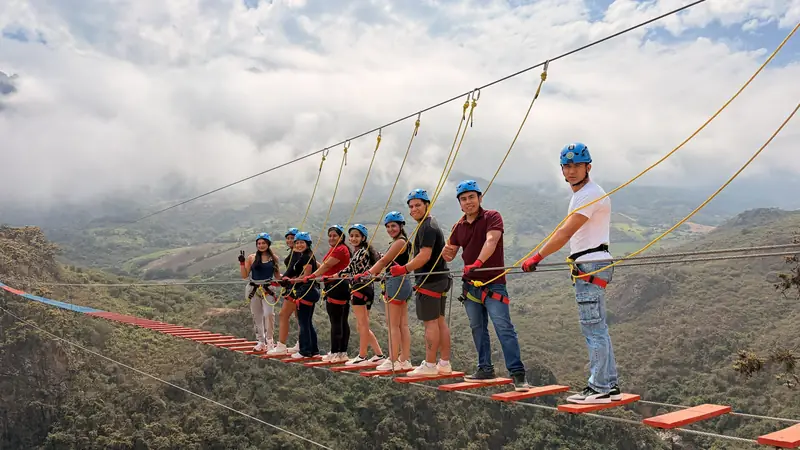 Viajeros sobre el puente tibetano con las nubes cubriendo los cerros