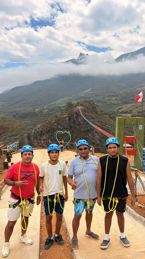 Cuatro visitantes con arnés y casco posando en la plataforma de salida