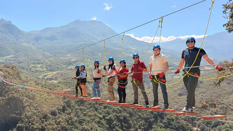 Grupo numeroso cruzando el puente tibetano acompañado por el guía