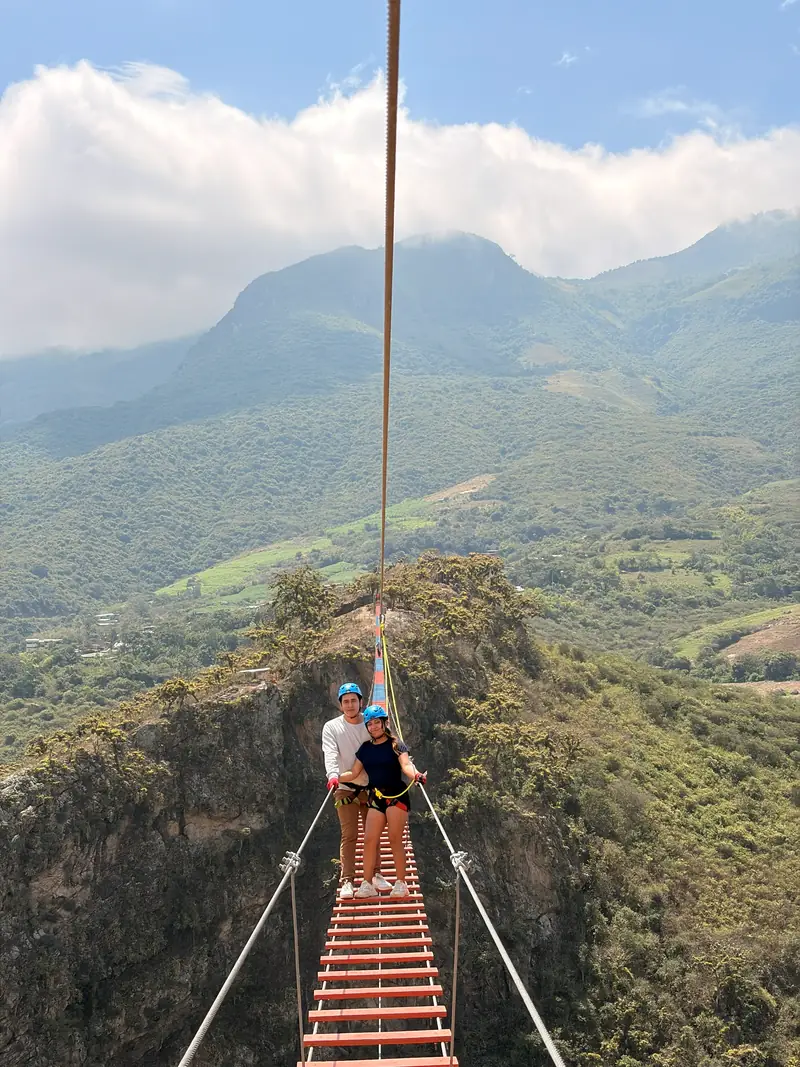 Puente colgante visto desde su entrada, con una viajera al fondo