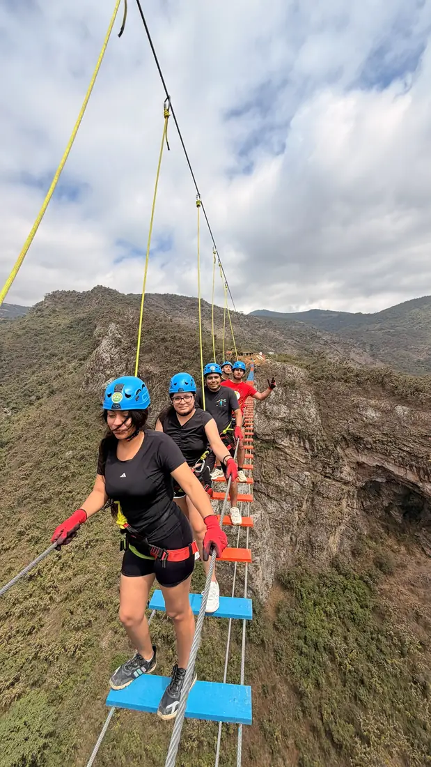 Dos viajeras cruzando el puente colgante agarradas de la línea de seguridad