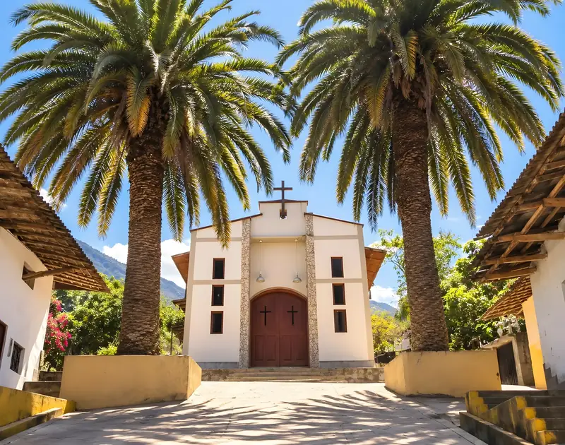 Capilla de Tocmoche, blanca y flanqueada por dos palmeras